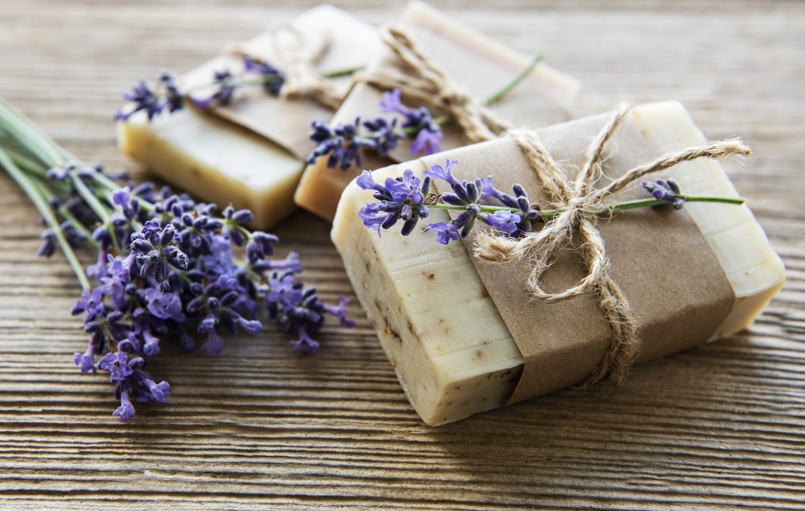 Bars of handmade soap with lavender flowers over  wood grunge background.